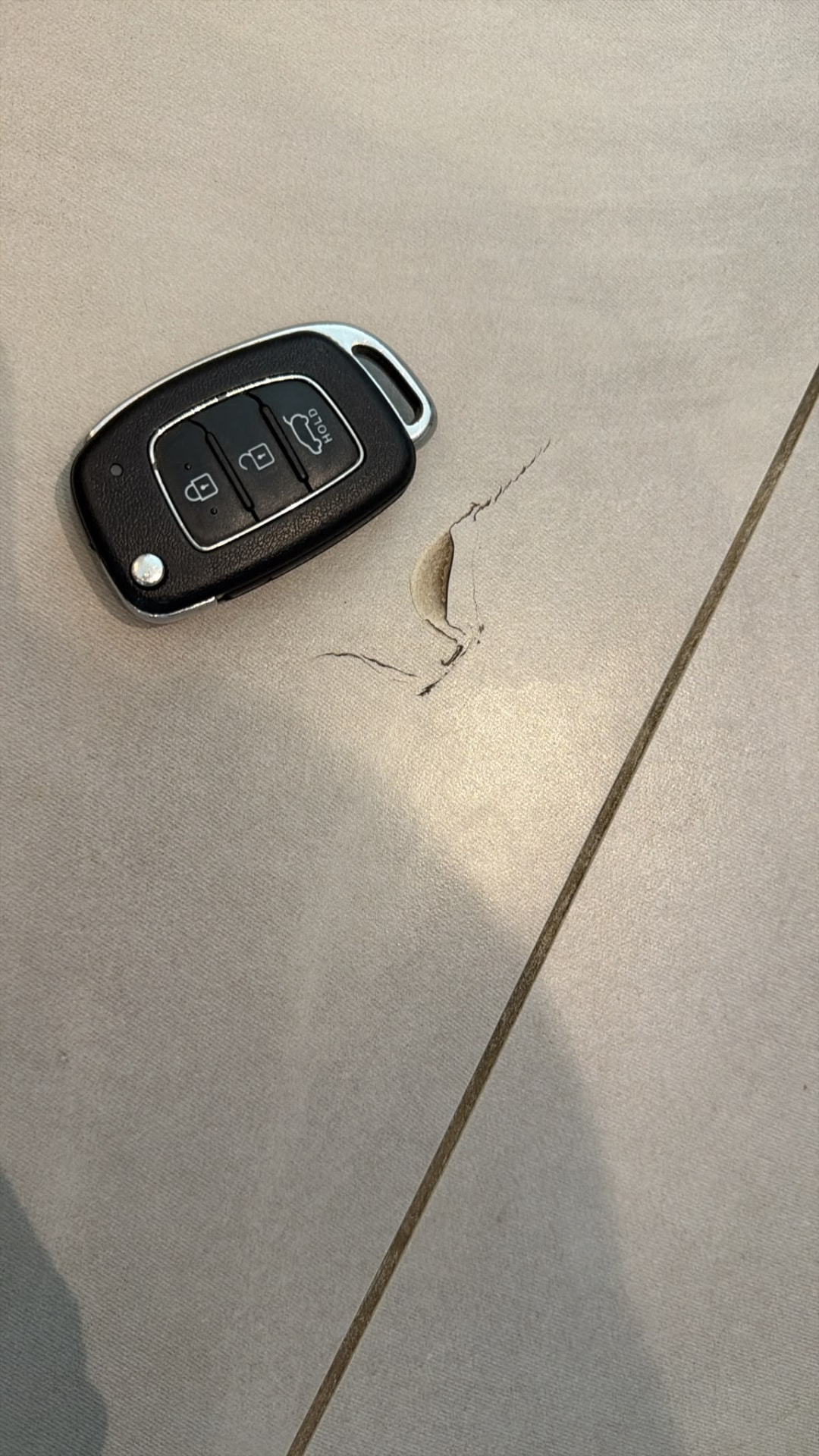 לפני התיקון — שבב באריח ריצוף באופקים לצד מפתח רכב להמחשת גודל