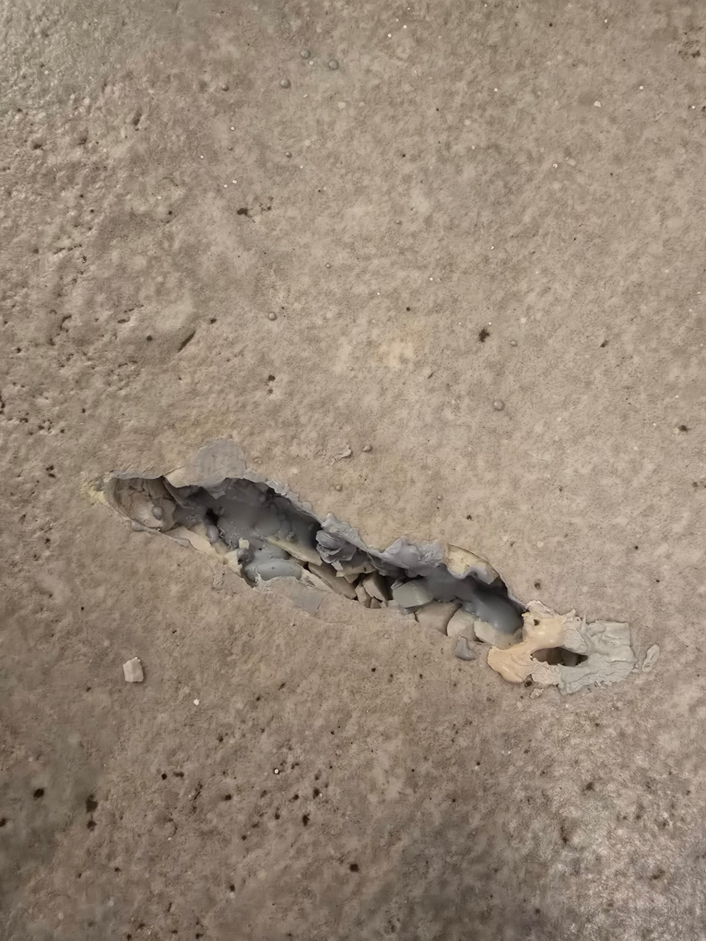 לפני התיקון — חור עמוק ושבר באריח גרניט פורצלן דמוי בטון